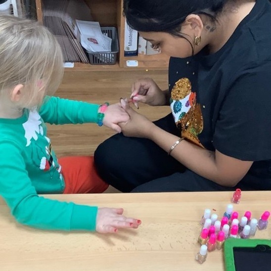 A key worker gently painting a child’s nails — a quiet, calm moment together