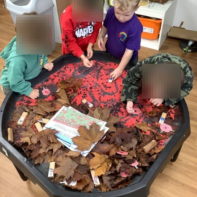 A child carefully cutting paper shapes with red scissors on a rainbow-striped craft table