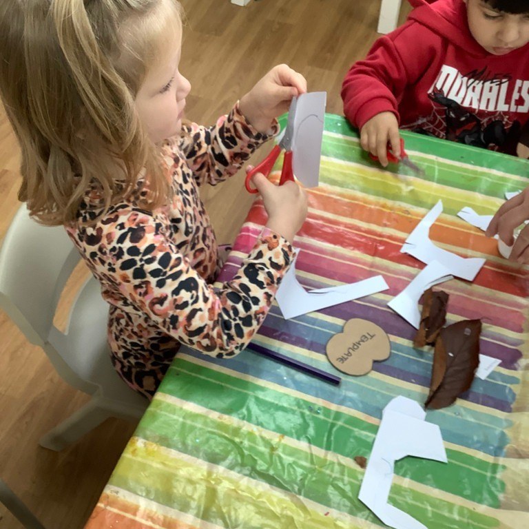 A staff member reading a picture book aloud to a small circle of children on a rug